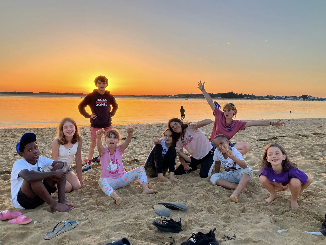 Des enfants sur une plage devant un couché de soleil